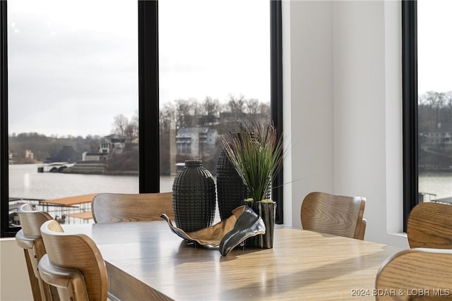 dining area featuring a water view, a wealth of natural light, and hardwood / wood-style flooring