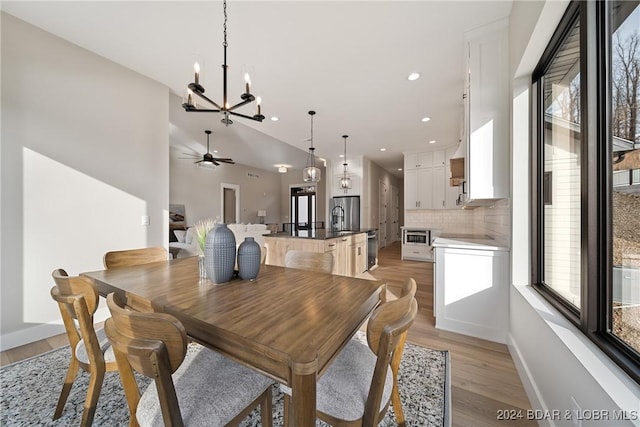 dining room with ceiling fan with notable chandelier, light hardwood / wood-style floors, and a healthy amount of sunlight