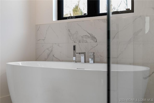 bathroom with a washtub and tile walls