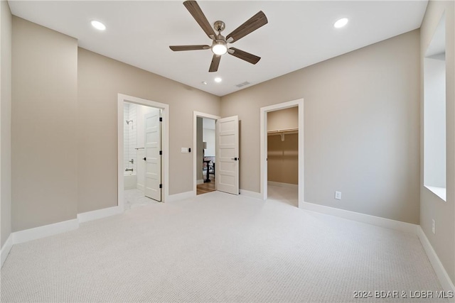 unfurnished bedroom with light carpet, a walk in closet, ceiling fan, connected bathroom, and a closet