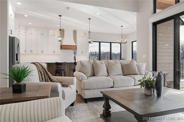 living room with hardwood / wood-style flooring, a notable chandelier, and sink