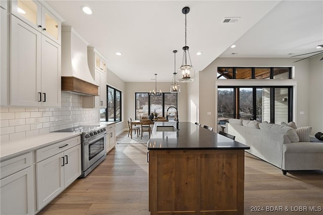 kitchen with stainless steel range, white cabinets, and custom exhaust hood