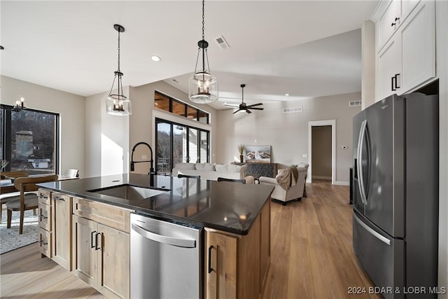 kitchen with a kitchen island with sink, sink, light hardwood / wood-style floors, white cabinetry, and stainless steel appliances