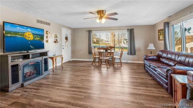 living room featuring a textured ceiling, dark hardwood / wood-style floors, and ceiling fan