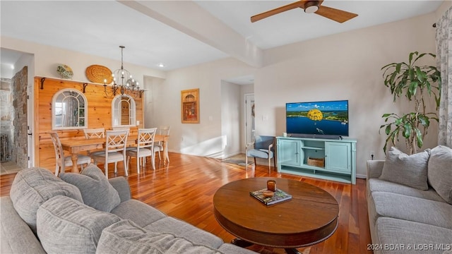 living room with wood-type flooring, beam ceiling, and ceiling fan with notable chandelier