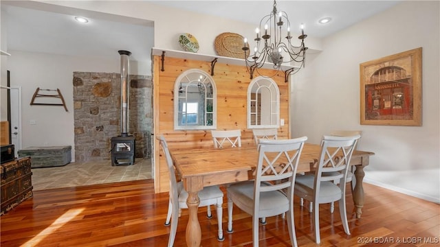 dining area with hardwood / wood-style flooring, a wood stove, and an inviting chandelier