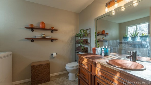 bathroom featuring vanity, independent washer and dryer, and toilet