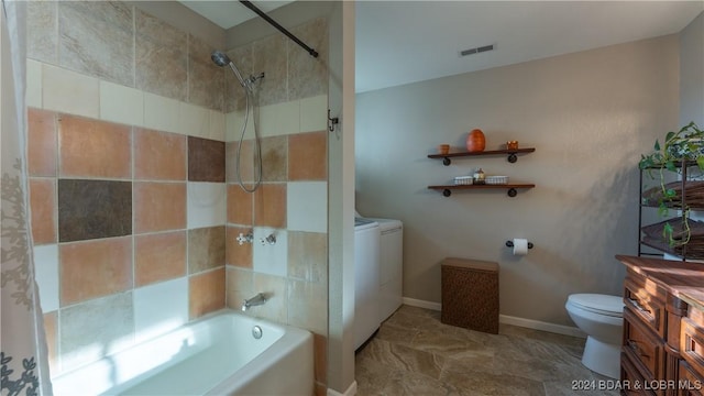 full bathroom featuring vanity, tiled shower / bath combo, independent washer and dryer, and toilet