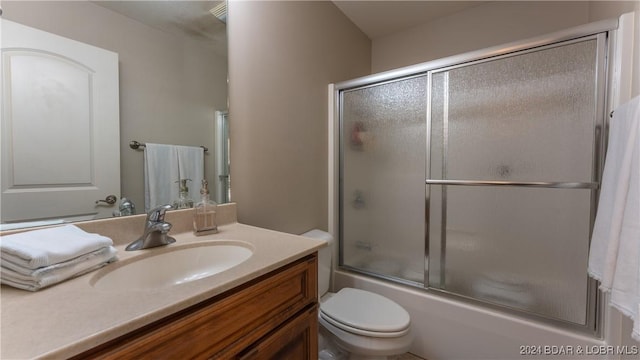 full bathroom featuring vanity, toilet, and bath / shower combo with glass door