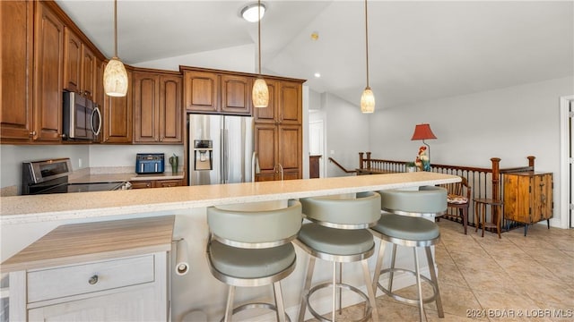 kitchen with a kitchen breakfast bar, decorative light fixtures, stainless steel appliances, and lofted ceiling