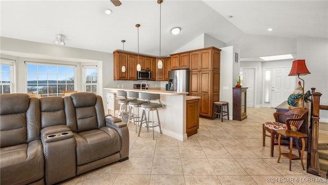 kitchen with a breakfast bar, lofted ceiling, decorative light fixtures, light tile patterned flooring, and stainless steel appliances