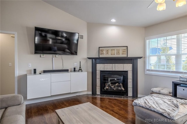 living room featuring a tile fireplace, ceiling fan, dark wood-type flooring, and lofted ceiling