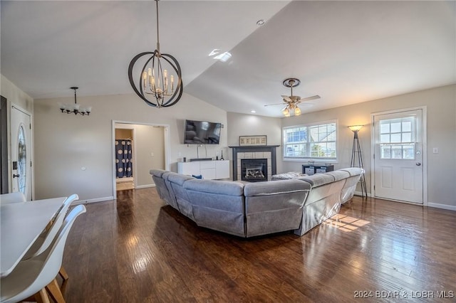 living room featuring a tile fireplace, ceiling fan with notable chandelier, dark wood-type flooring, and lofted ceiling