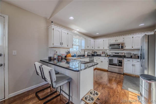 kitchen featuring dark wood-type flooring, white cabinets, sink, kitchen peninsula, and stainless steel appliances