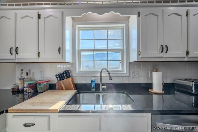 kitchen featuring white cabinets, decorative backsplash, and sink