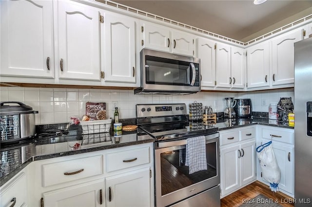 kitchen featuring white cabinetry, appliances with stainless steel finishes, and dark stone counters