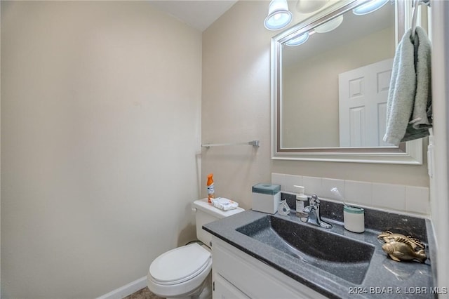 bathroom featuring decorative backsplash, toilet, and vanity