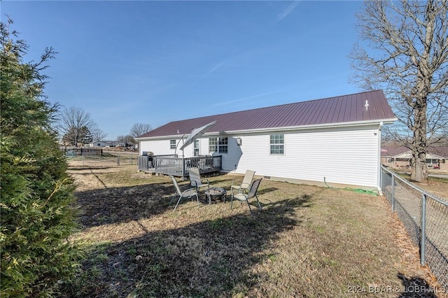 back of house with a yard, an outdoor fire pit, and a wooden deck