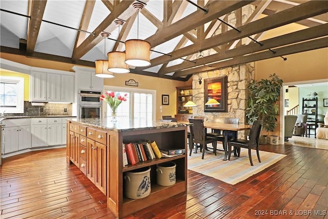 kitchen featuring white cabinetry, decorative light fixtures, a kitchen island, ceiling fan, and dark stone counters