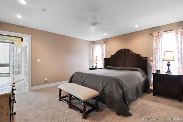 bedroom with ceiling fan, light colored carpet, and multiple windows