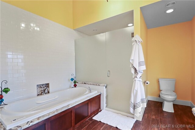 bathroom with toilet, hardwood / wood-style floors, and a washtub