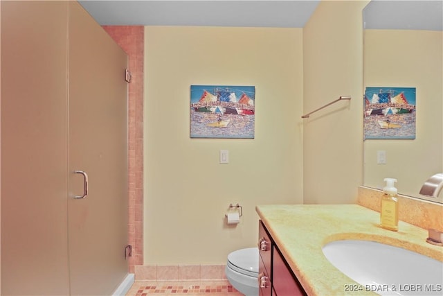 bathroom with vanity, a shower with shower door, tile patterned floors, and toilet