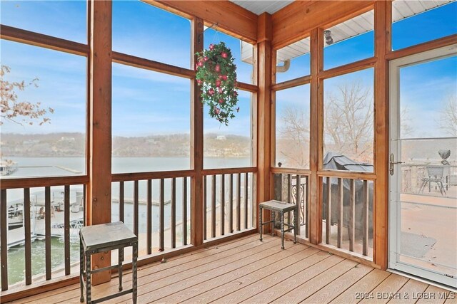 sunroom with beamed ceiling, a water view, and a wealth of natural light