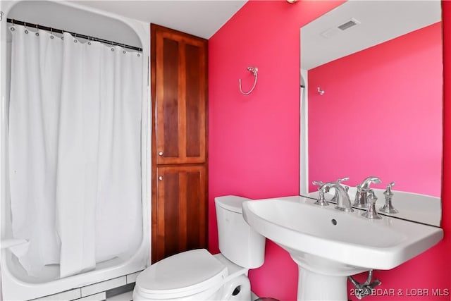 bathroom with sink, curtained shower, and toilet