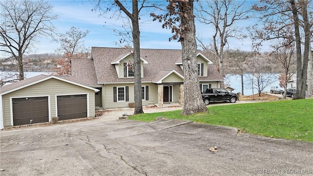 cape cod-style house featuring a garage, a water view, and a front lawn