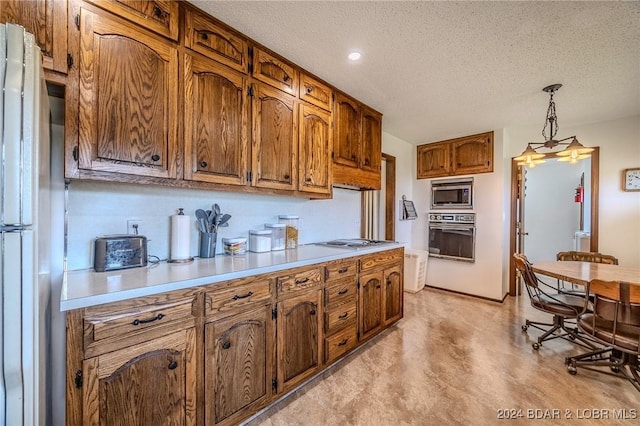 kitchen with refrigerator, a textured ceiling, decorative light fixtures, black oven, and stainless steel microwave