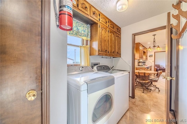 laundry area with cabinets, a textured ceiling, and washing machine and dryer