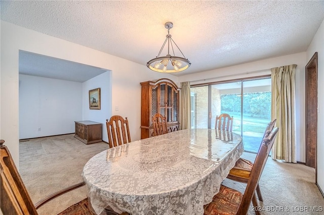 dining area with a textured ceiling, light carpet, and a chandelier