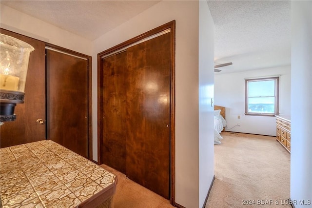 unfurnished bedroom with a textured ceiling, ceiling fan, and light carpet