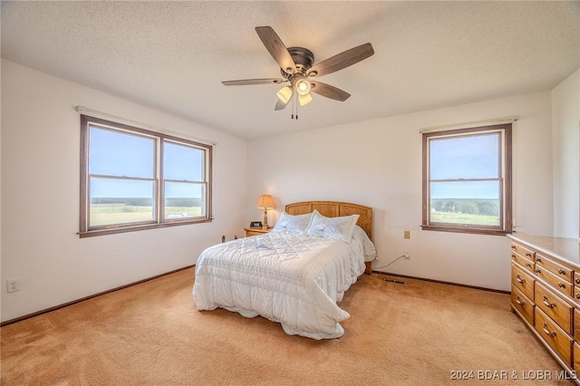 carpeted bedroom featuring ceiling fan and a textured ceiling