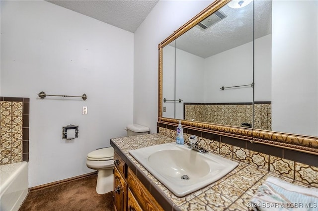 bathroom featuring vanity, a textured ceiling, toilet, and a washtub