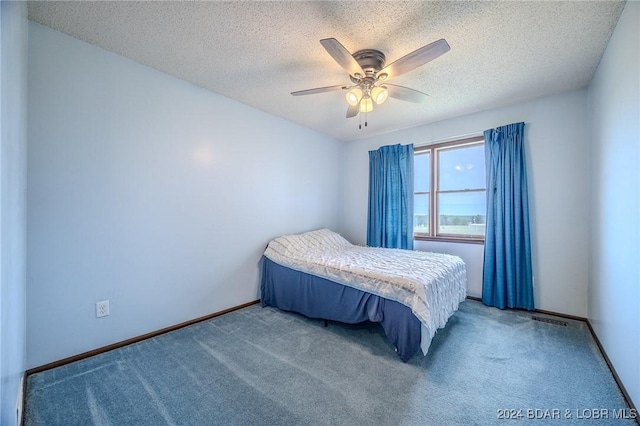 bedroom with a textured ceiling, carpet floors, and ceiling fan