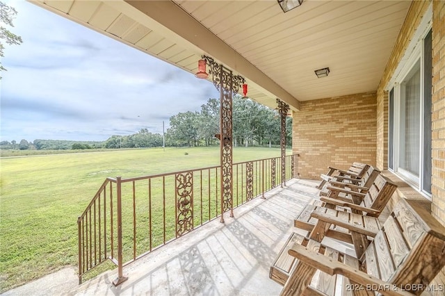 wooden terrace featuring a lawn and a rural view