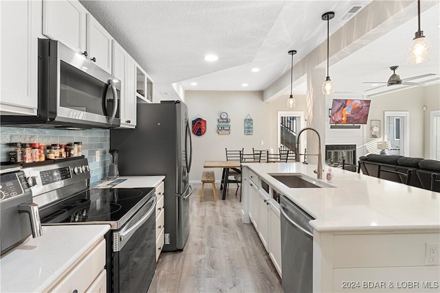 kitchen featuring pendant lighting, sink, appliances with stainless steel finishes, white cabinetry, and tasteful backsplash