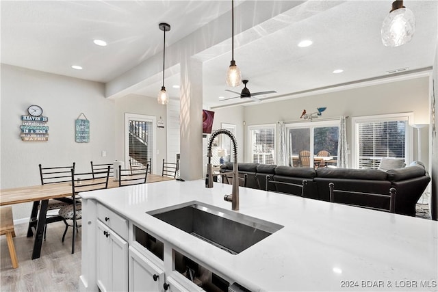 kitchen featuring decorative light fixtures, white cabinetry, sink, ceiling fan, and light hardwood / wood-style flooring