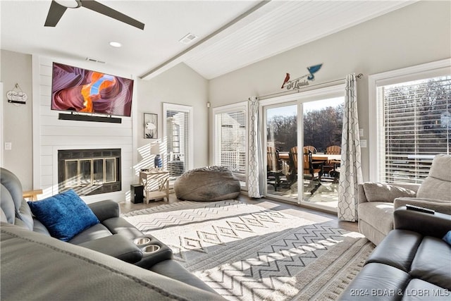 living room featuring hardwood / wood-style flooring, ceiling fan, a fireplace, and vaulted ceiling