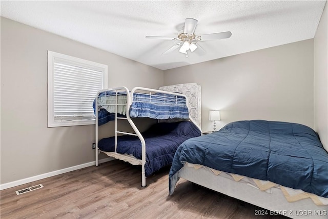 bedroom featuring ceiling fan, wood-type flooring, and a textured ceiling