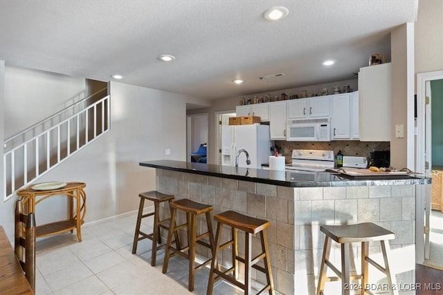 4800 Eagleview Dr Unit 241A, Osage Beach, MO 65065 - kitchen with white appliances, decorative backsplash, a breakfast bar, white cabinetry, and recessed lighting