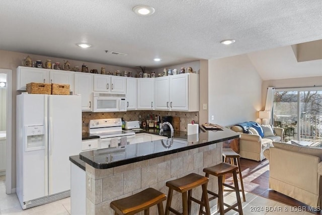 4800 Eagleview Dr Unit 241A, Osage Beach, MO 65065 - kitchen featuring white appliances, open floor plan, white cabinetry, a breakfast bar area, and a textured ceiling
