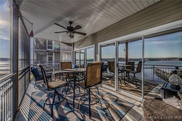 sunroom / solarium with ceiling fan and a water view