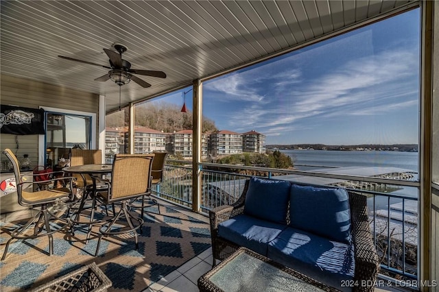 sunroom / solarium featuring ceiling fan and a water view