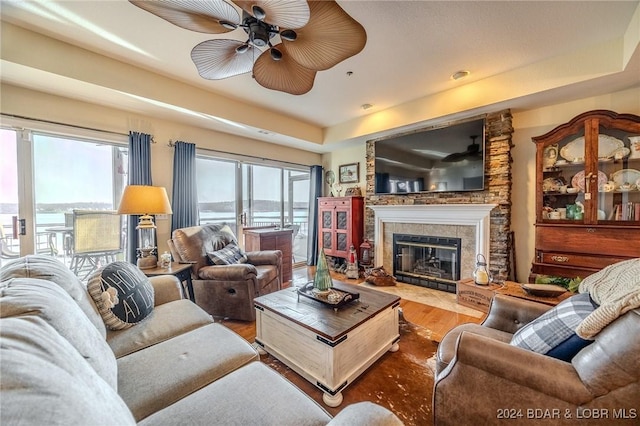 living room featuring hardwood / wood-style floors, ceiling fan, and a tile fireplace