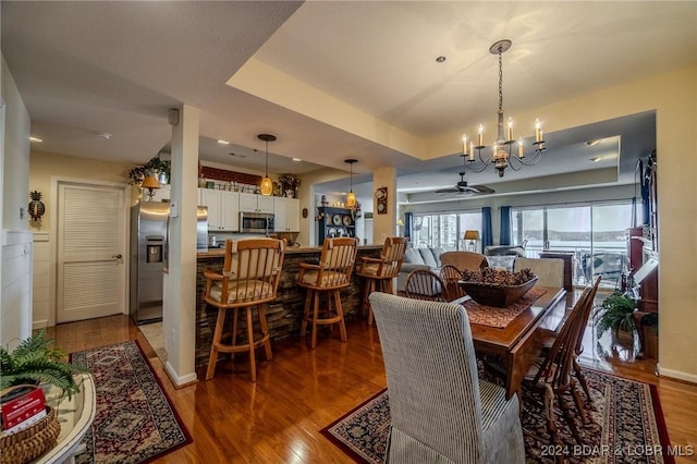 dining room featuring a raised ceiling, wood-type flooring, and ceiling fan with notable chandelier