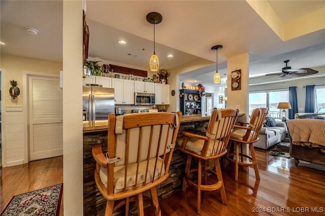 kitchen with white cabinets, wood-type flooring, stainless steel appliances, and hanging light fixtures