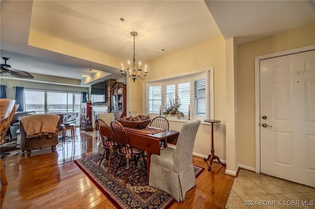 dining room featuring a tray ceiling, light hardwood / wood-style floors, and ceiling fan with notable chandelier