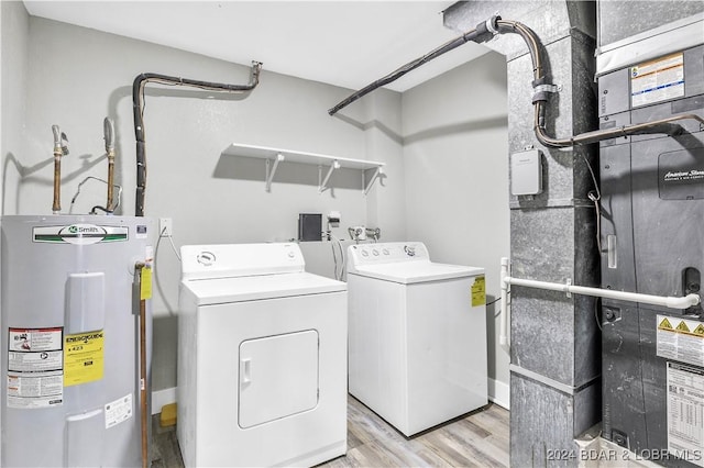 clothes washing area featuring washing machine and clothes dryer, light hardwood / wood-style flooring, and water heater